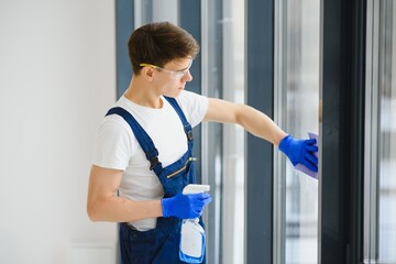 Cleaning service came to clean new house. Hardworking man carefully clean window. Side view