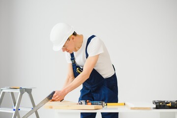 carpenter sawing white board during apartment renovating