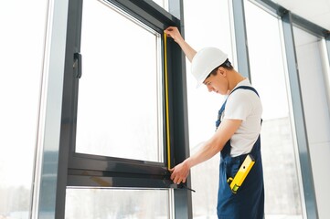 Professional handyman installing window at home.