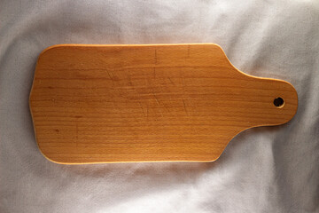 Wooden cutting board on the linen, mockup for design, flat lay. Concept of kitchenware