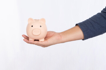 Hand holding a pink piggy bank isolated on white background