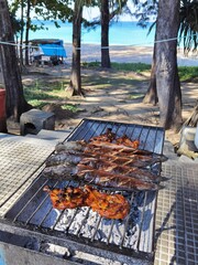 Chiken and fish barbeque in the metal braizer ashore.