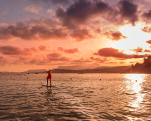 Fototapeta premium Person doing paddle surf in with a beautiful sunset on the beach