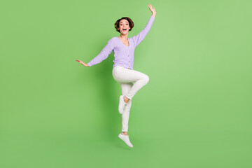 Fototapeta premium Full length photo of delighted lady jump raise knee open mouth unbelievable offer isolated on green color background