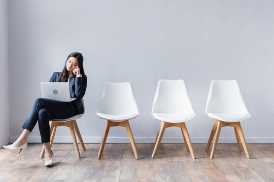Asian businesswoman using laptop in hall while waiting job interview