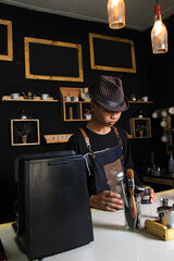 Indonesian Barista Prepare coffee drinks for customers at the coffee shop. portrait of a coffee shop employee making coffee at the bar. the process of making warm drinks with a vintage color concept