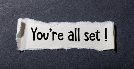 You're all set! text written on a small piece of paper and a black background.