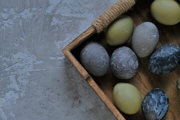 Easter holiday. Gray, blue  marbled easter eggs in wooden tray on gray concrete background.Spring festive easter background.Easter symbol. copy space.