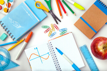 Children education, accessories, school supplies, colored pencils, an apple and a notebook on a white background. Schoolchildren study and creativity concept and back to school concept.