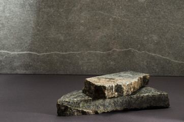 Closeup of grey marble pieces against bright marble wall.Empty space.Template for product presentation