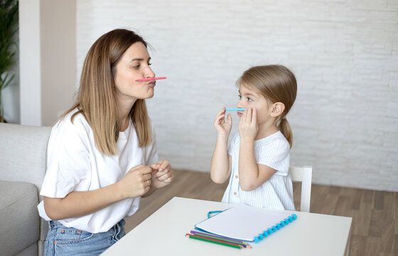 Speech therapy for kids. Young woman and little girl make exercises, activities and game for better speech.