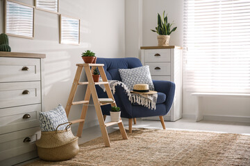 Stylish living room interior with wooden ladder and comfortable armchair