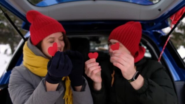 Close up portrait cheerful couple faces looking through red paper hearts. St Valentines Day celebration, romantic relationships, feelings and love concept