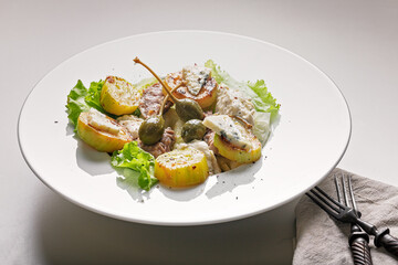 Quick and healthy food recipes. Salad with grilled zucchini, vegetables, herbs, turkey sous vide meat, blue cheese and capers on white plate. Mediterranean dish recipes. Selective focus. Close-up