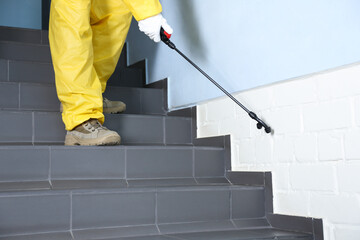 Pest control worker spraying pesticide on stairs indoors, closeup