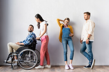 Asian woman smiling at disabled man near pregnant woman in hall