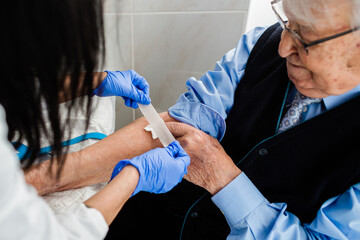 Nurse drawing blood from an elderly man in his home. Home care.