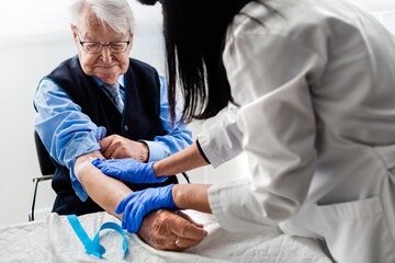 Nurse drawing blood from an elderly man in his home. Home care.