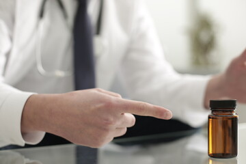The doctor's hand points to the medicine that is on the glass table