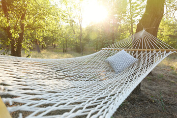 Comfortable net hammock with soft pillow at green garden, closeup