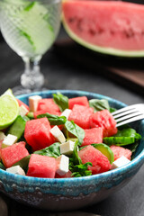 Delicious salad with watermelon served on black table, closeup
