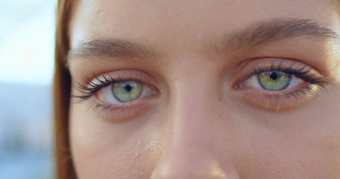 Close up of young caucasian blond woman with green eyes in bus stop at street. Portrait of beautiful happy stylish girl looking into camera. Train station. Travel, tourism concept