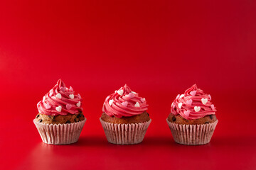 Cupcakes decorated with sugar hearts for Valentine's Day on red background	