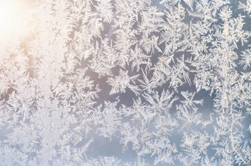 Frosty patterns on the window glass illuminated by the sun as a winter background