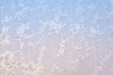 Winter ice frost on the glass as a light blue background