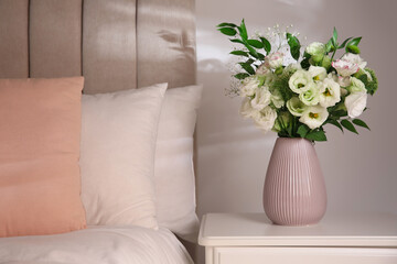 Bouquet of beautiful flowers on nightstand in bedroom, space for text. Interior design