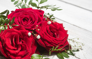 flower composition of red roses close up on a wooden white table. Valentine's Day greeting card.