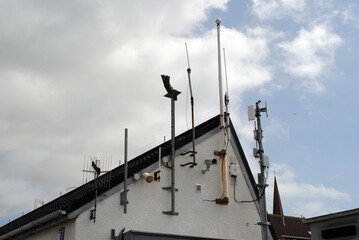 Fototapeta na wymiar Radio Aerials on Roof of Building against Cloudy Sky