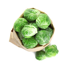 Fototapeta premium Fresh Brussels sprouts in paper bag on white background, top view