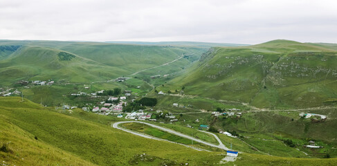 Beautiful mountain scenery. Mountains covered with green trees with residential settlements. In...
