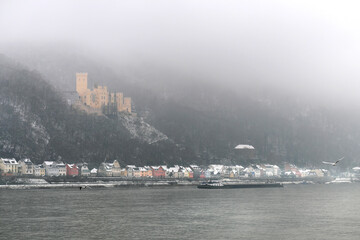 Binnenschiff auf dem Rhein bei Koblenz vor dem Schloss Stolzenfels im Winter und Berghang im Nebel...