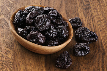 Dried plums on wooden background.