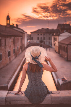 ragazza con cappello che guarda tramonto a comacchio