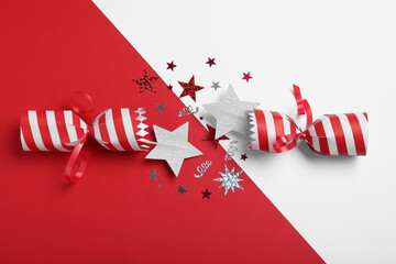 Open Christmas cracker with shiny confetti on color background, top view