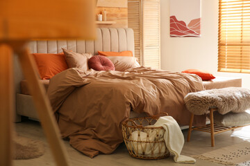Bed with brown linens in cozy bedroom. Interior design