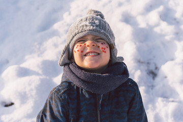 Joyful boy with red hearts on his face. Love concept