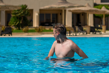 Naklejka premium Real people concept, beautiful young man, teenage boy swimming and having fun in pool in vacation. happiness and nice body for enjoyed people live an alternative lifestyle as vacation