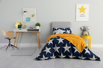 Bed with star patterned linens in child's bedroom. Interior design