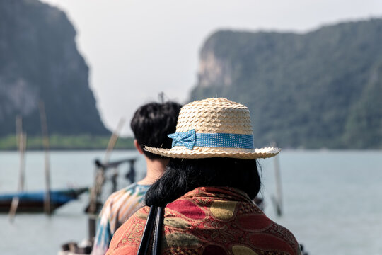 woman wearing straw hat Go on an island vacation with family, with mountains and sea as background pictures.