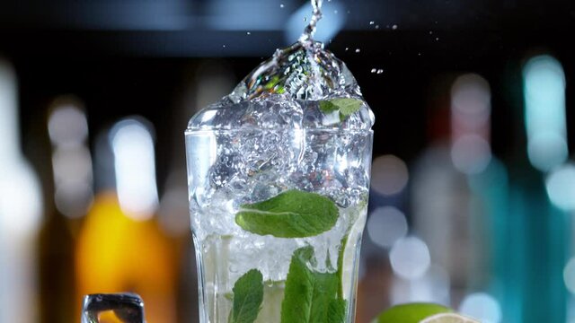 Super slow motion of falling ice cube into mojito drink, camera movement. Filmed on high speed cinema camera, 1000 fps.