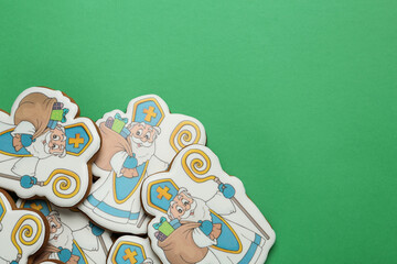 Tasty gingerbread cookies on green background, flat lay with space for text. St. Nicholas Day celebration