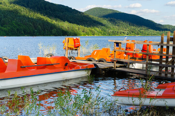Orange catamarans on lake moored at the pier. Hipster lifestyle. Active summer vacation.