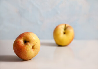 Two ripe ugly apples lie on a light background. Horizontally. Minimalism concept. Healthy nutrition.