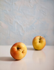 Two ripe ugly apples lie on a light background. Vertical. Minimalism concept. Healthy nutrition.