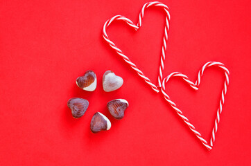 Festive red background. Hearts and sweet candies. Valentine Day. 14 of February. Ideas of gifts. Flat lay, top view.
