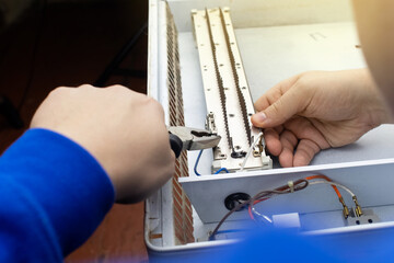 An electrical repairman repairs a convector. A close-up of an open heater and its interior. Technical assistance concept